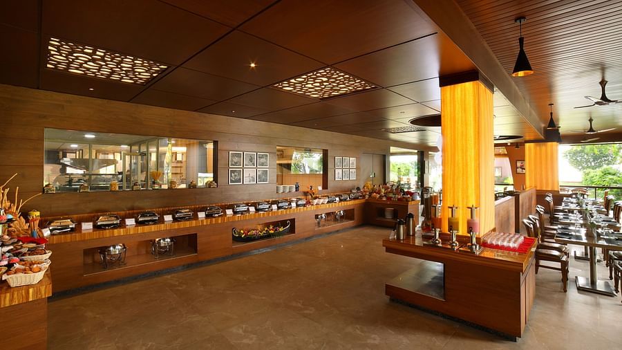 Aambal Restaurant at Uday Backwater Resort, with tables set on one side overlooking the outdoors and buffet counters on the other