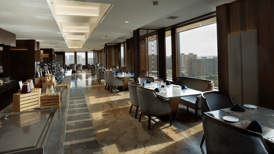 An expansive fine-dining room with well-spaced tables and large windows providing natural light - Praveg's Grand Eulogia, Ahmedabad