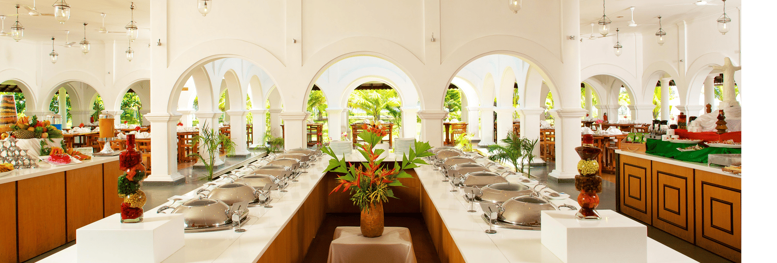 An indoor restaurant buffet area featuring a U-shaped counter with food warmers set against white arched walls | Le Pondy
