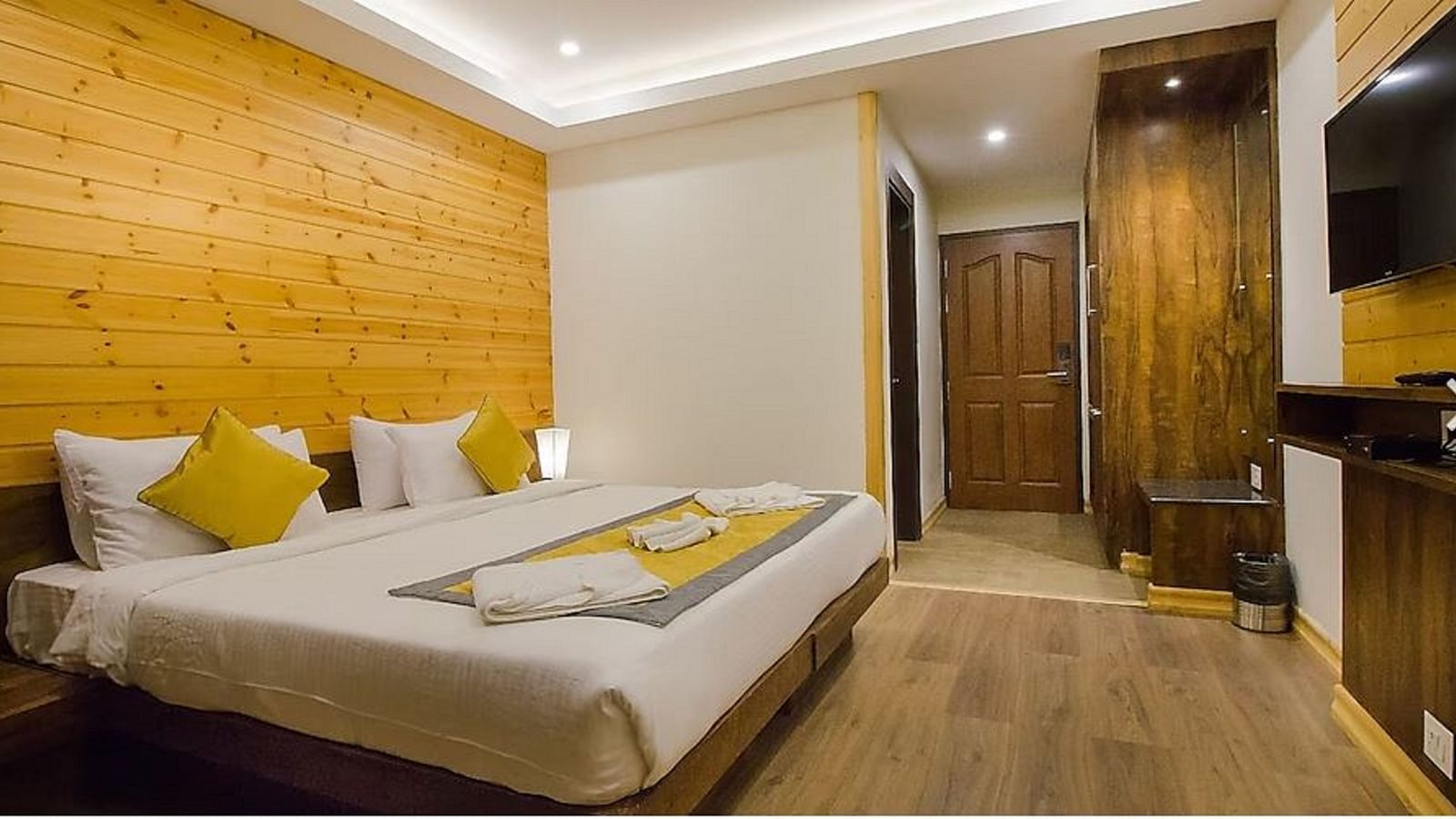 An image of a deluxe room with a bed, bed side table, and flat screen TV - Yashshree Sanderling, Darjeeling