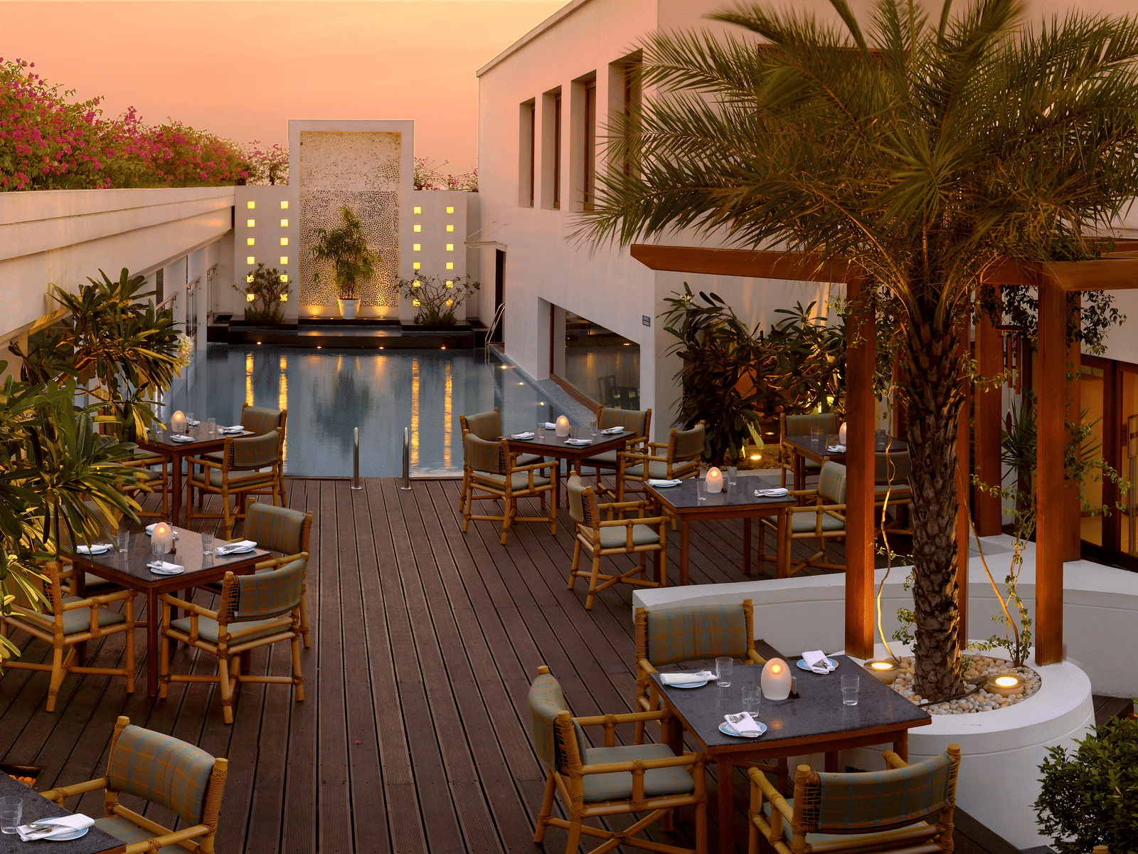 Outdoor dining area with a pool and palm trees - The Raintree, St. Mary's Road