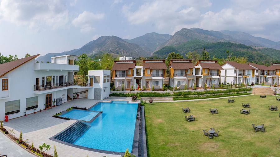 A picturesque resort with a swimming pool, surrounded by lush greenery and majestic mountains