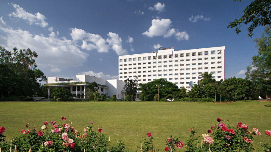 A panoramic facade shot of Clarks Amer, Jaipur, a 5-star Hotel in Jaipur, with an expansive lawn in the foreground under a clear blue sky.
