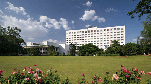 A panoramic facade shot of Clarks Amer, Jaipur, a 5-star Hotel in Jaipur, with an expansive lawn in the foreground under a clear blue sky.