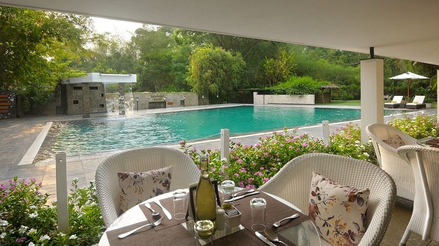 Outdoor poolside dining area with tables set and a pool in the background.