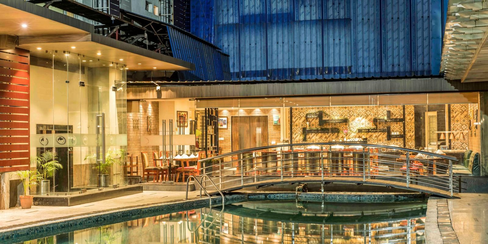 Hotel exterior at night showcasing a swimming pool, a bridge, and illuminated walkways | The Citi Residenci Hotel Durgapur