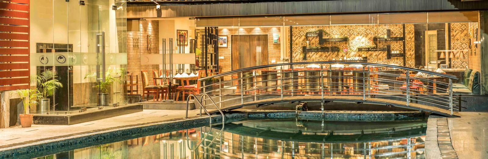 Hotel exterior at night showcasing a swimming pool, a bridge, and illuminated walkways | The Citi Residenci Hotel Durgapur