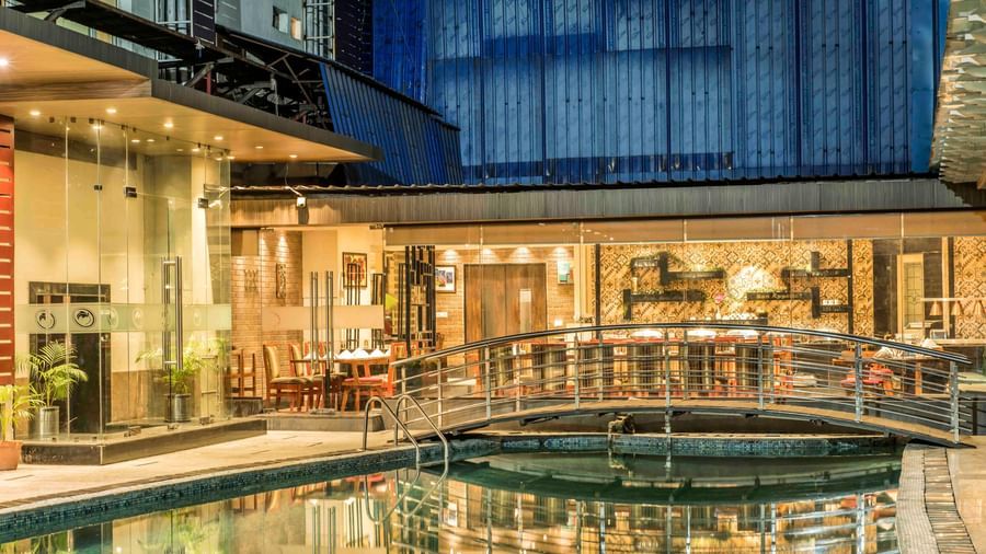 Hotel exterior at night showcasing a swimming pool, a bridge, and illuminated walkways | The Citi Residenci Hotel Durgapur