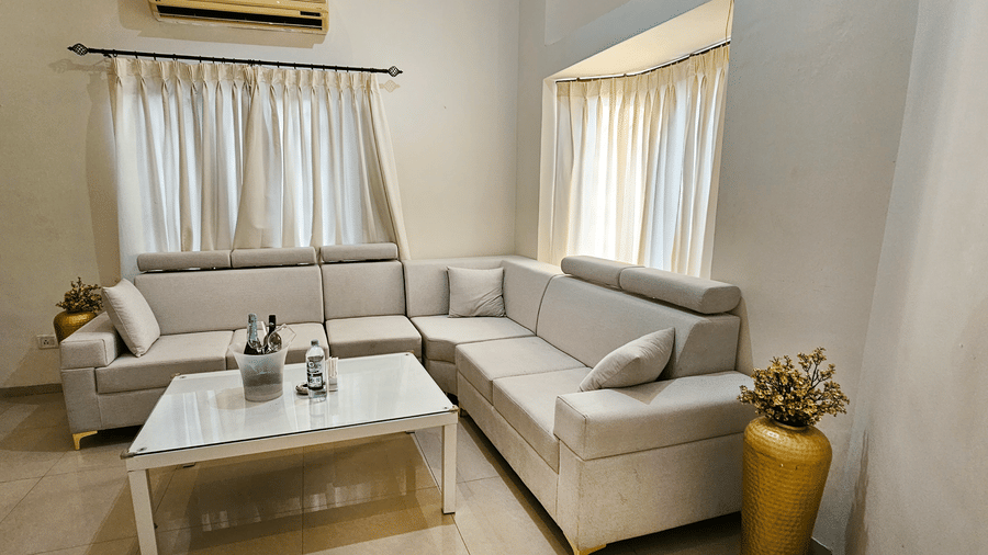 An L-shaped couch with a glass-top coffee table in the living area of Amara Villa, Nagoa.
