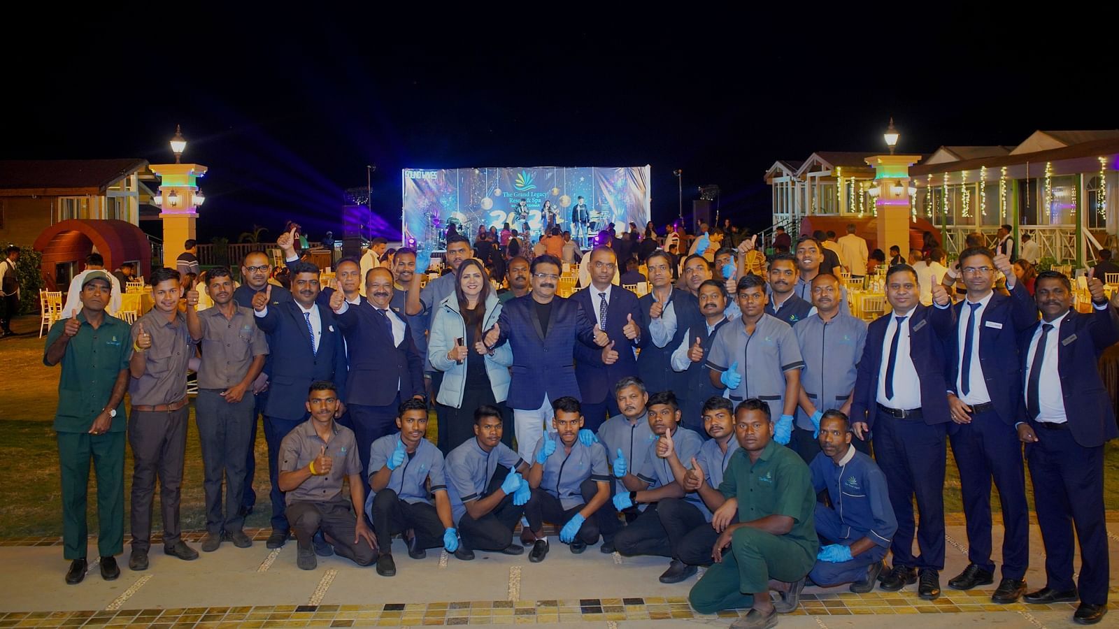 Team group photo taken outdoors during an evening event - The Grand Legacy Resort & Spa