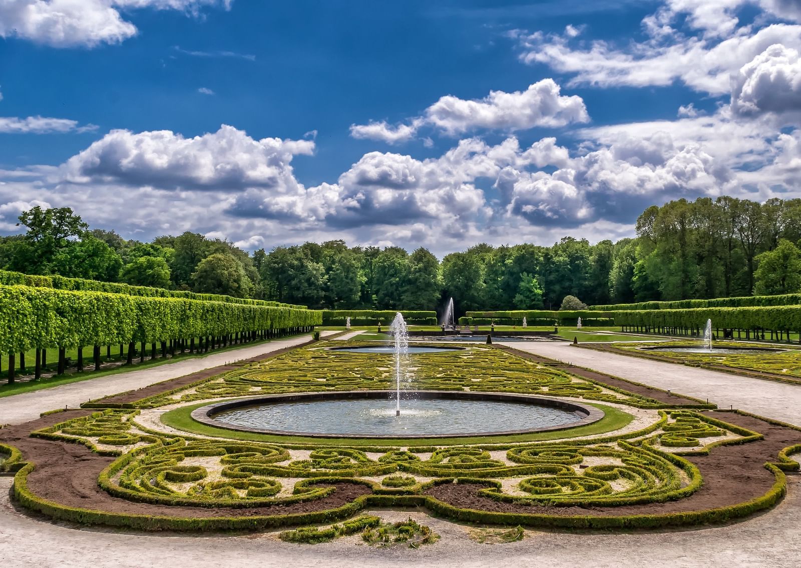 An overview of a garden with a fountain in the centre and trees surrounding it.