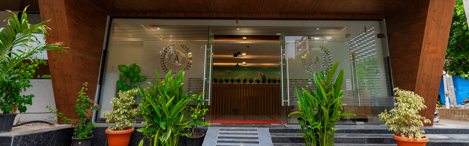 An image of entrance with plants around and a glass wall which takes you to Hotel Aerotel, Hyderabad - A Unit of Comfort Hometel