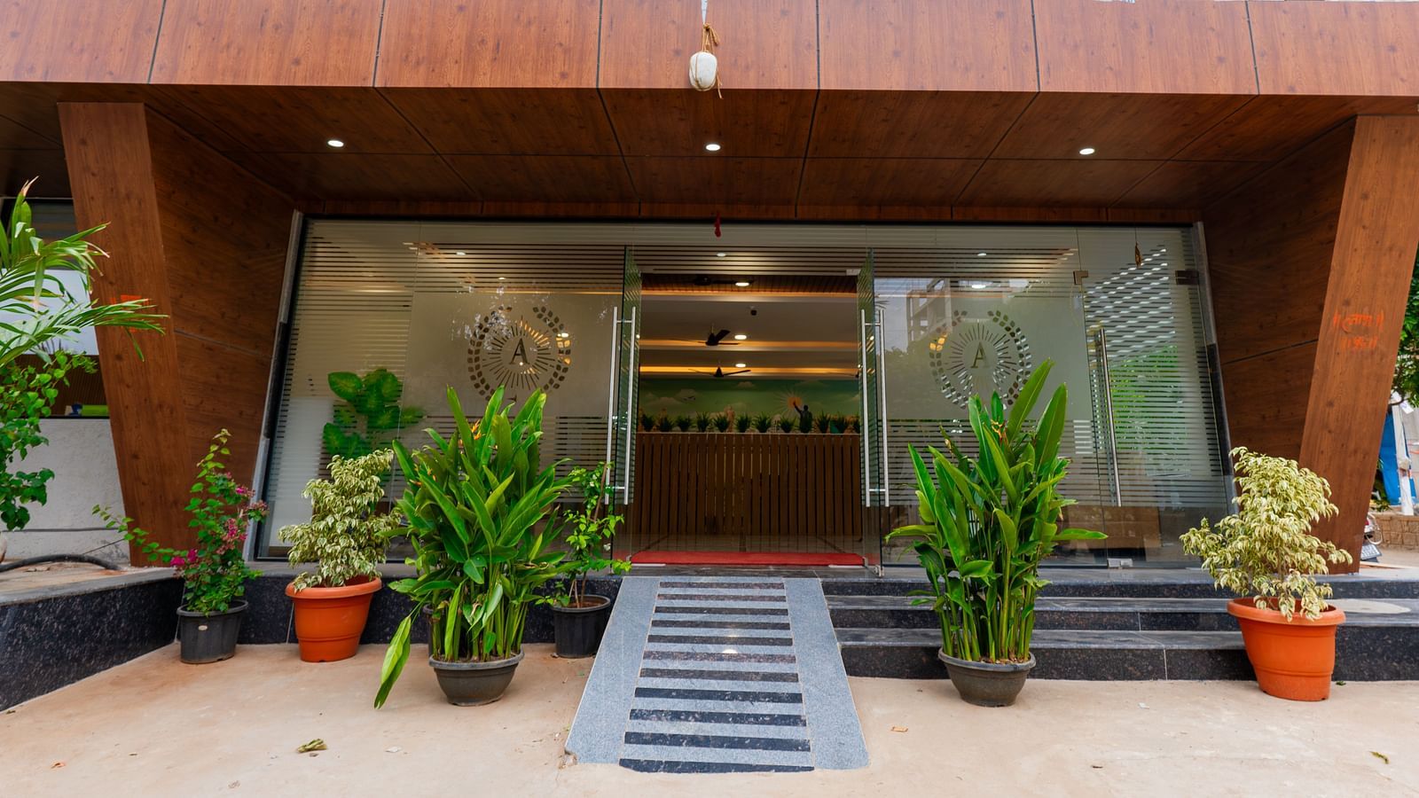 An image of entrance with plants around and a glass wall which takes you to Hotel Aerotel, Hyderabad - A Unit of Comfort Hometel