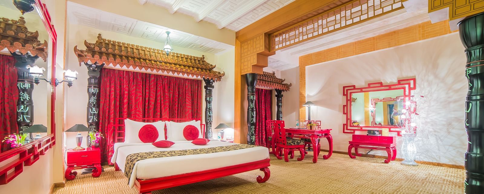 A grand hotel suite with an opulent red and white decor, large bed, and seating area, reflecting a traditional style at Sitara Luxury Hotel in Hyderabad near Ramoji Film City.