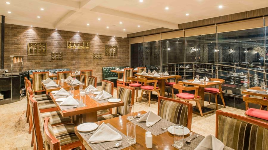 Hotel restaurant with wooden tables and chairs, set for a meal in a warm ambience | The Citi Residenci Hotel Durgapur