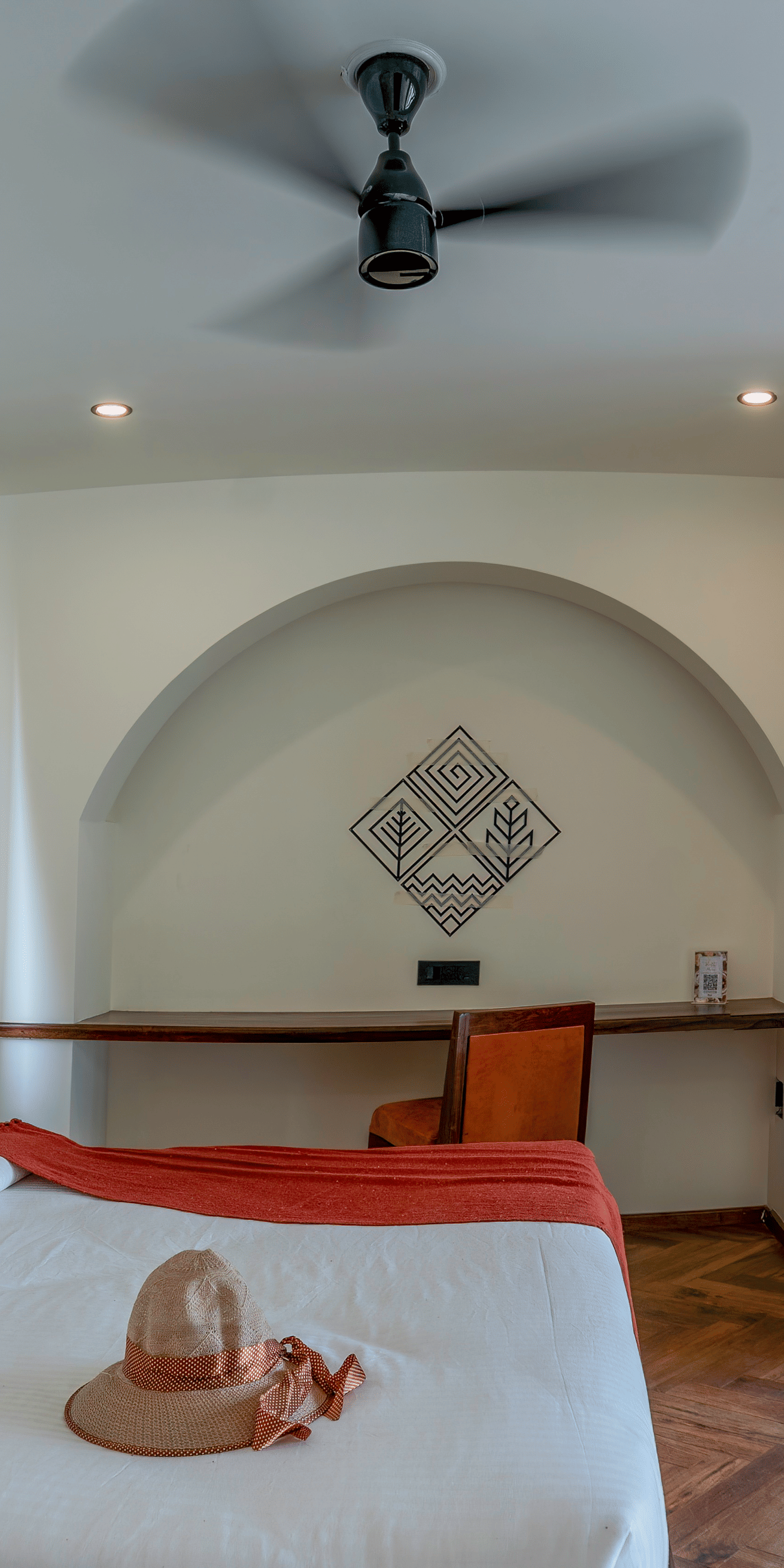 A bedroom with a large bed, an arched entryway leading to a sitting area with a sofa, and sliding glass doors opening to an outdoor area at The Golden Tusk, Jim Corbett