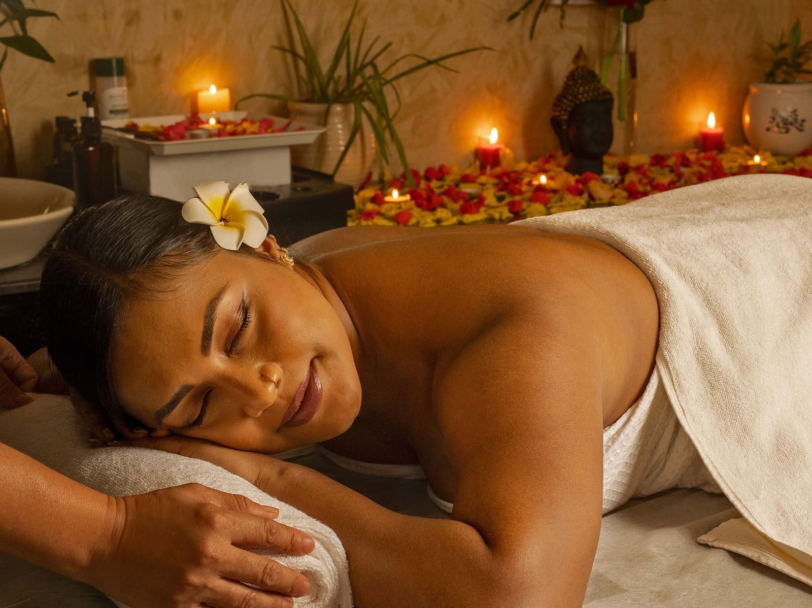 A close-up of a woman enjoying a relaxing massage in a serene spa setting. The warm lighting, candles, and flowers add to the tranquil ambiance - Coral Reef Resort & Spa, Havelock