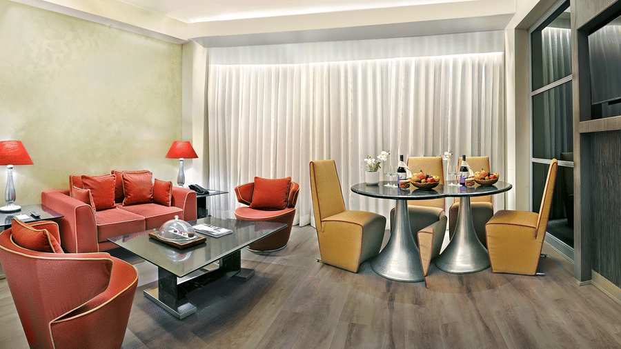 Suite at The Sonnet, Kolkata with a seating area, armchairs, side table and floor to ceiling curtains.