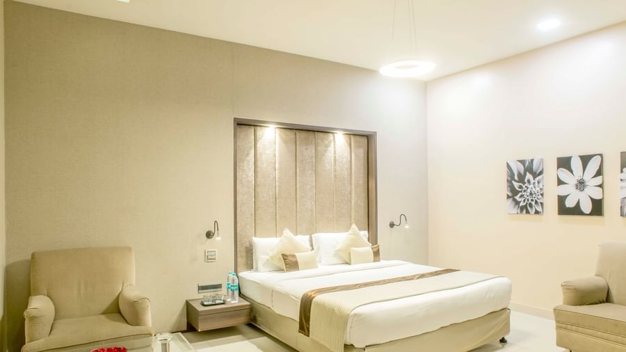Another view of a well-lit hotel room with a king size bed and a comfortable armchair | The Citi Residenci Hotel Durgapur