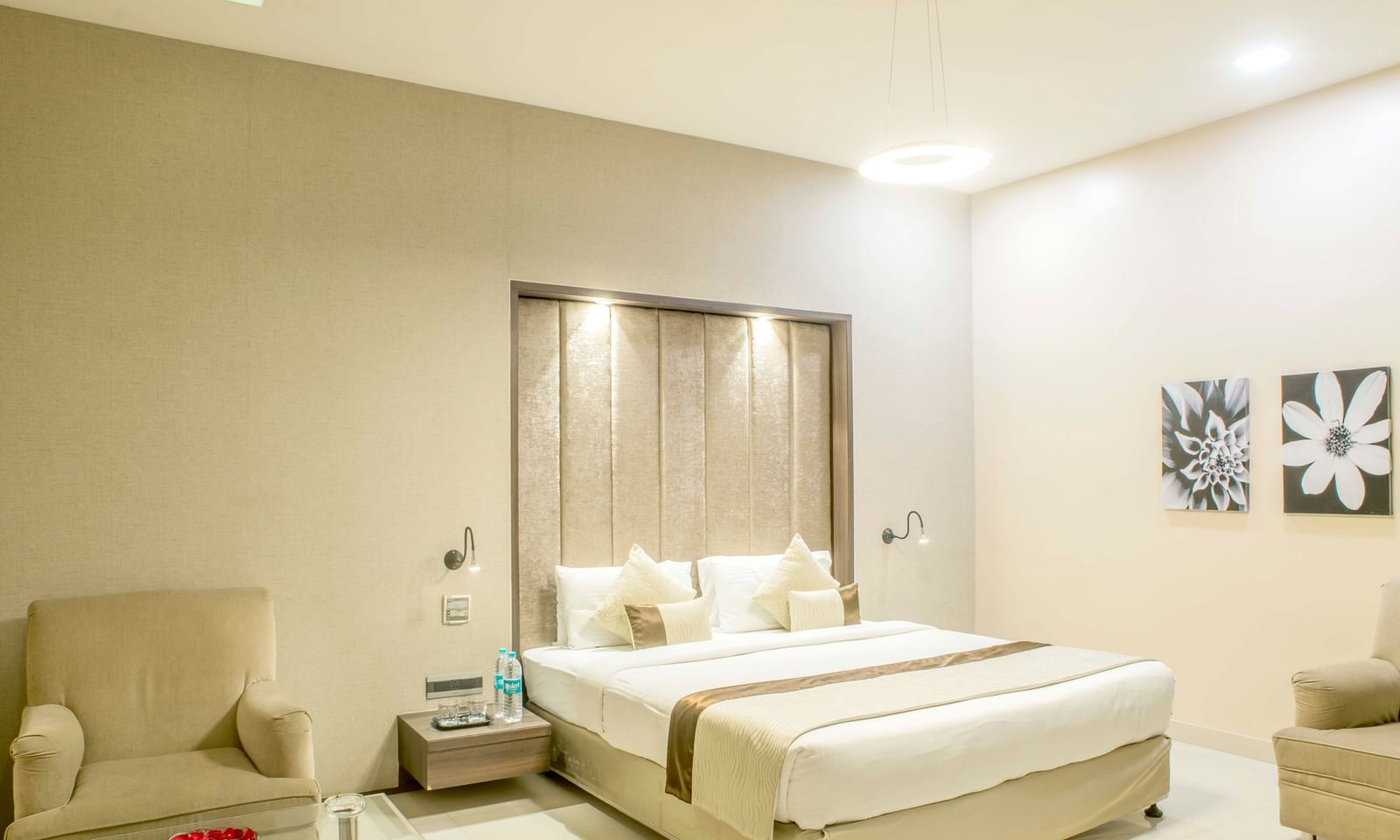 Another view of a well-lit hotel room with a king size bed and a comfortable armchair | The Citi Residenci Hotel Durgapur