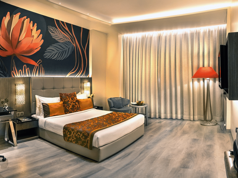 Superior room at The Sonnet, Kolkata featuring a king-size bed, stylish interiors, a work desk, lounge chair, floor-to-ceiling curtains, and warm ambient lighting.