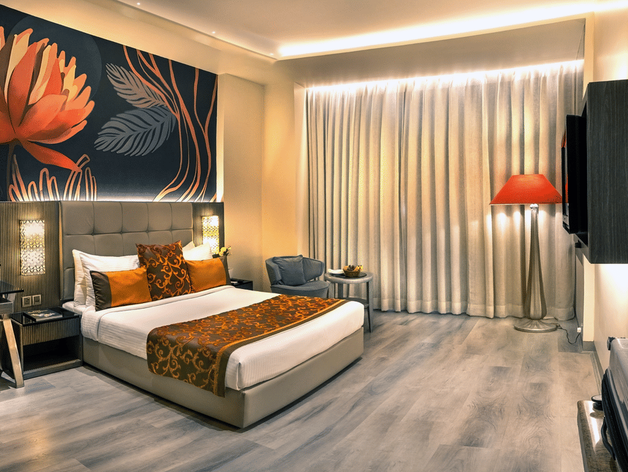 Superior room at The Sonnet, Kolkata featuring a king-size bed, stylish interiors, a work desk, lounge chair, floor-to-ceiling curtains, and warm ambient lighting.