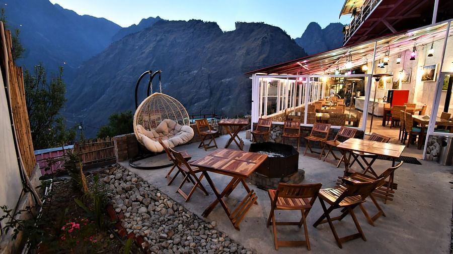 image of an outdoor seating area with folding wooden chairs arranged in a circle with mountain views in the background at the tattva, joshimath