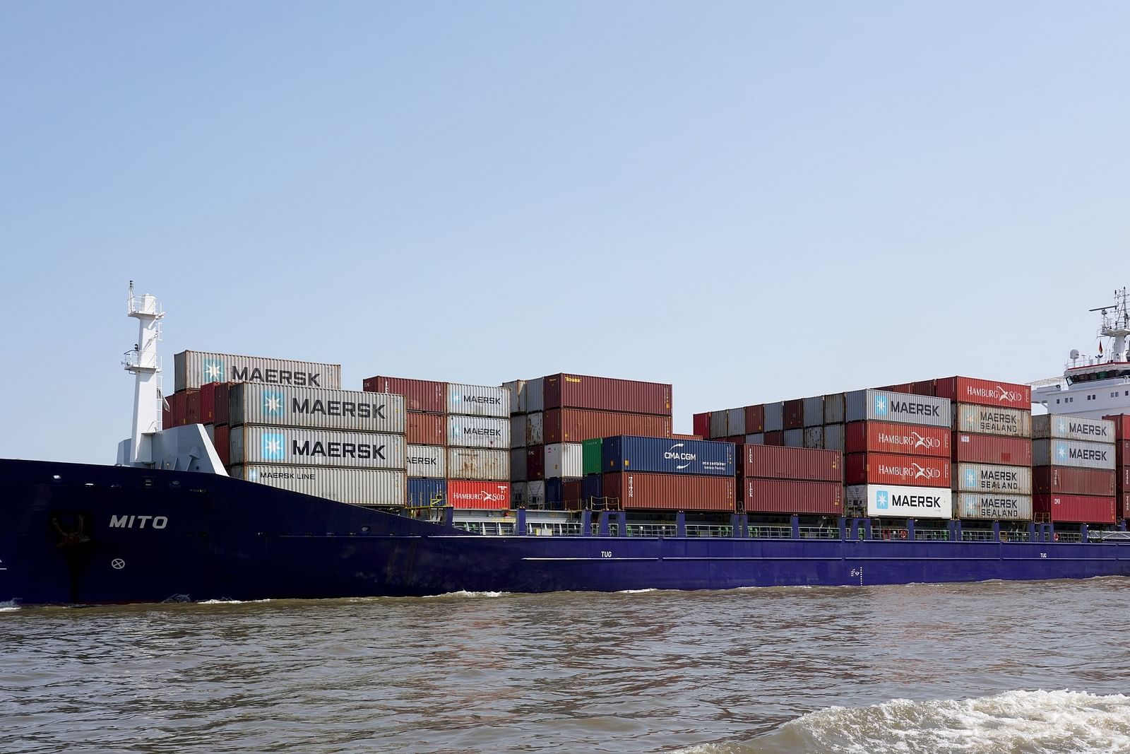 A far out view of a ship carrying many containers floating on a waterbody.