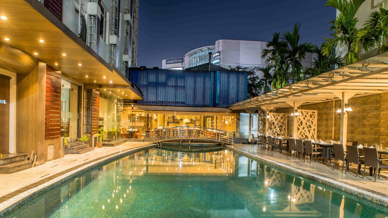 Hotel swimming pool at night surrounded by lounge chairs and illuminated by artificial lights | The Citi Residenci Hotel Durgapur