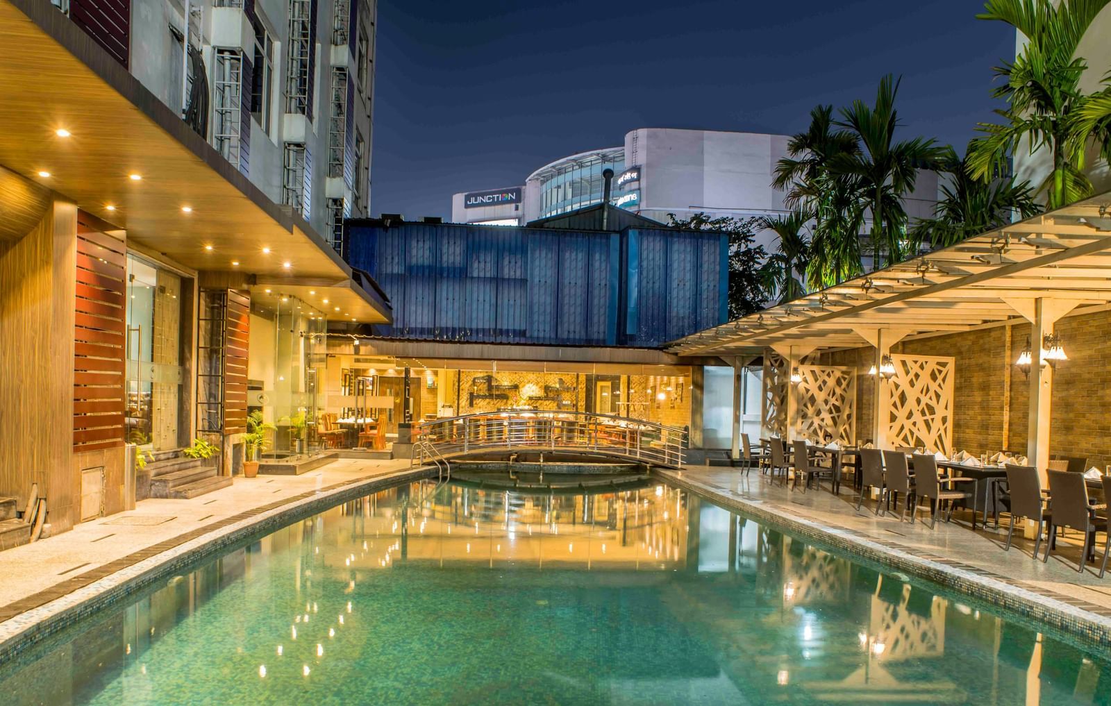 Hotel swimming pool at night surrounded by lounge chairs and illuminated by artificial lights | The Citi Residenci Hotel Durgapur
