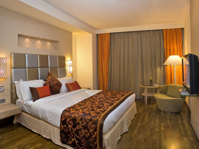 Interior of a hotel room showcasing its furnishings and amenities, including a bed, a desk, a TV and a chair- The Sonnet, Kolkata.