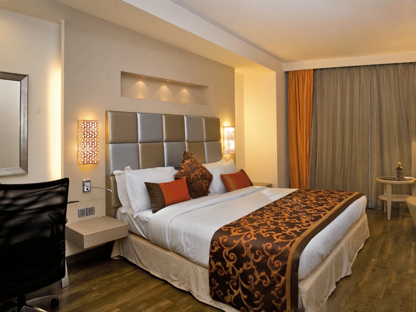 Interior of a hotel room showcasing its furnishings and amenities, including a bed, a desk, a TV and a chair- The Sonnet, Kolkata.