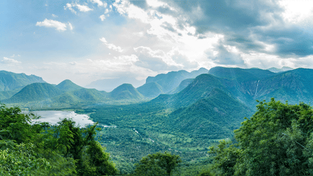 Expansive valley and layered Kodaikanal mountains of the Western Ghats under dramatic sunlight.