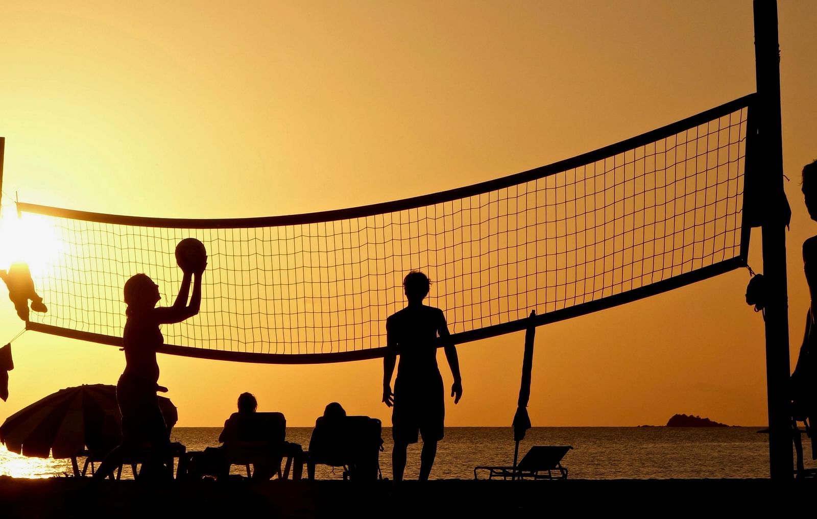 People playing beach volleyball during sunset