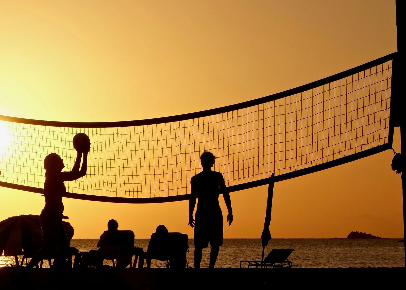 People playing beach volleyball during sunset