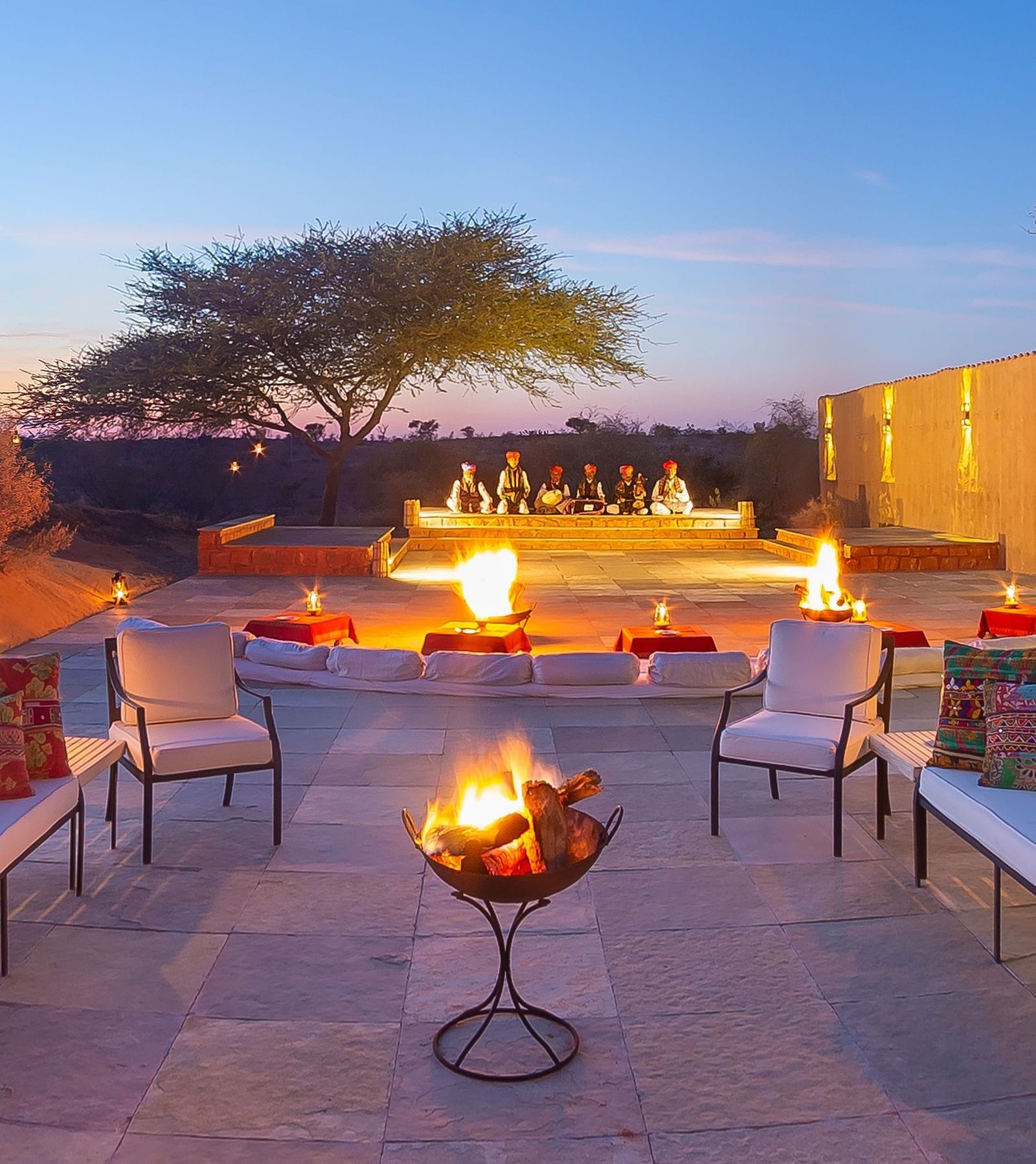 An outdoor seating area features plush sofas and a central fire pit, perfect for evening gatherings under the desert sky - MANVAR Resort & Desert Camp