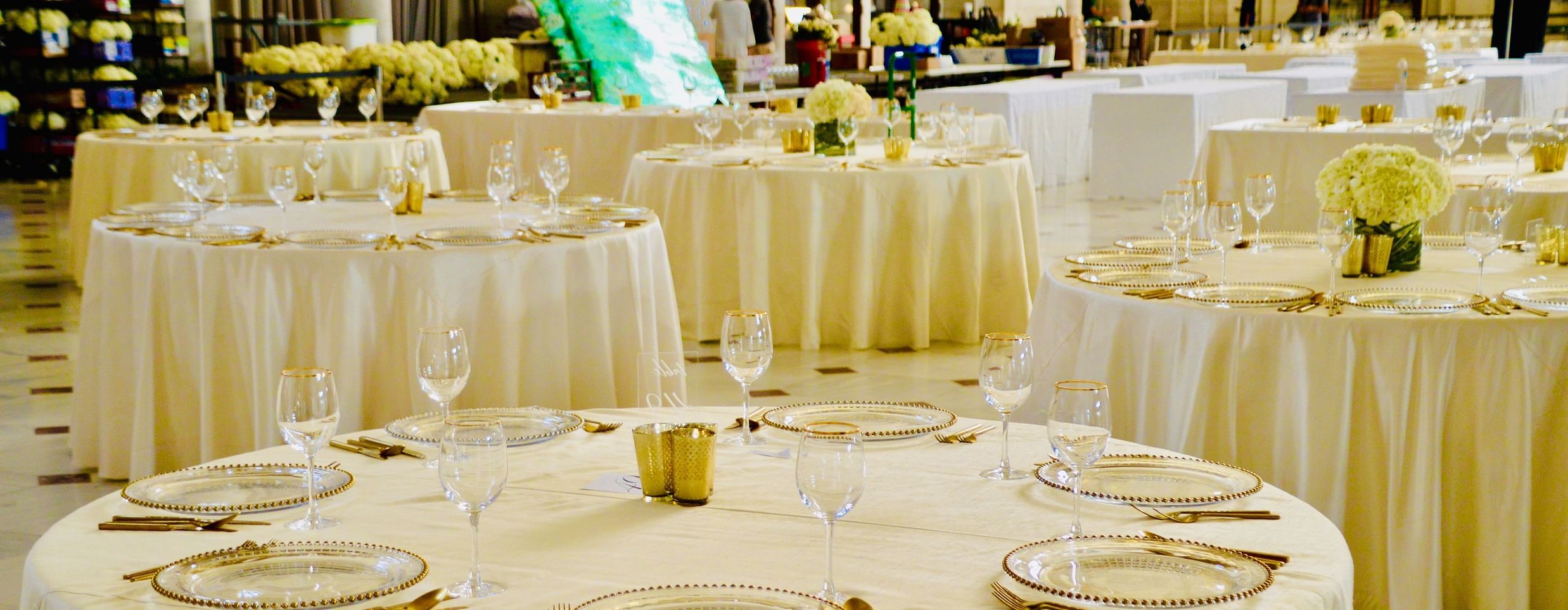 A beautifully arranged dining table with white linens, glasses, and dinnerware, ready for a special event or celebration.