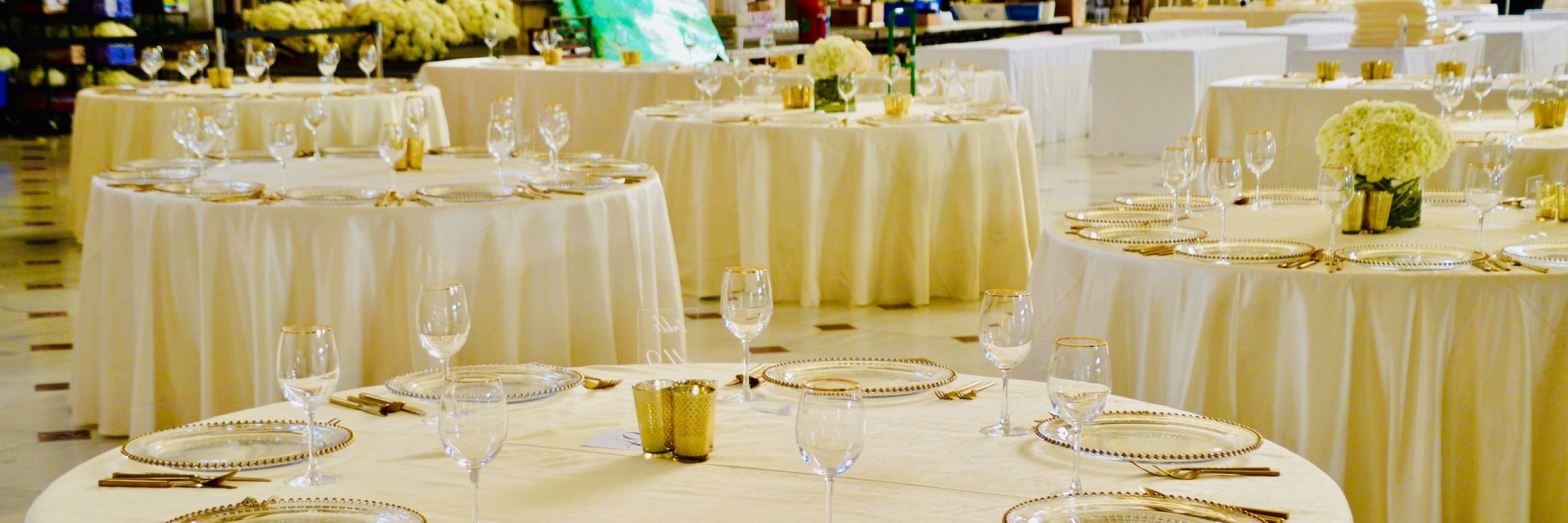 A banquet hall with round table seating arrangements and cutlery on the tables already set