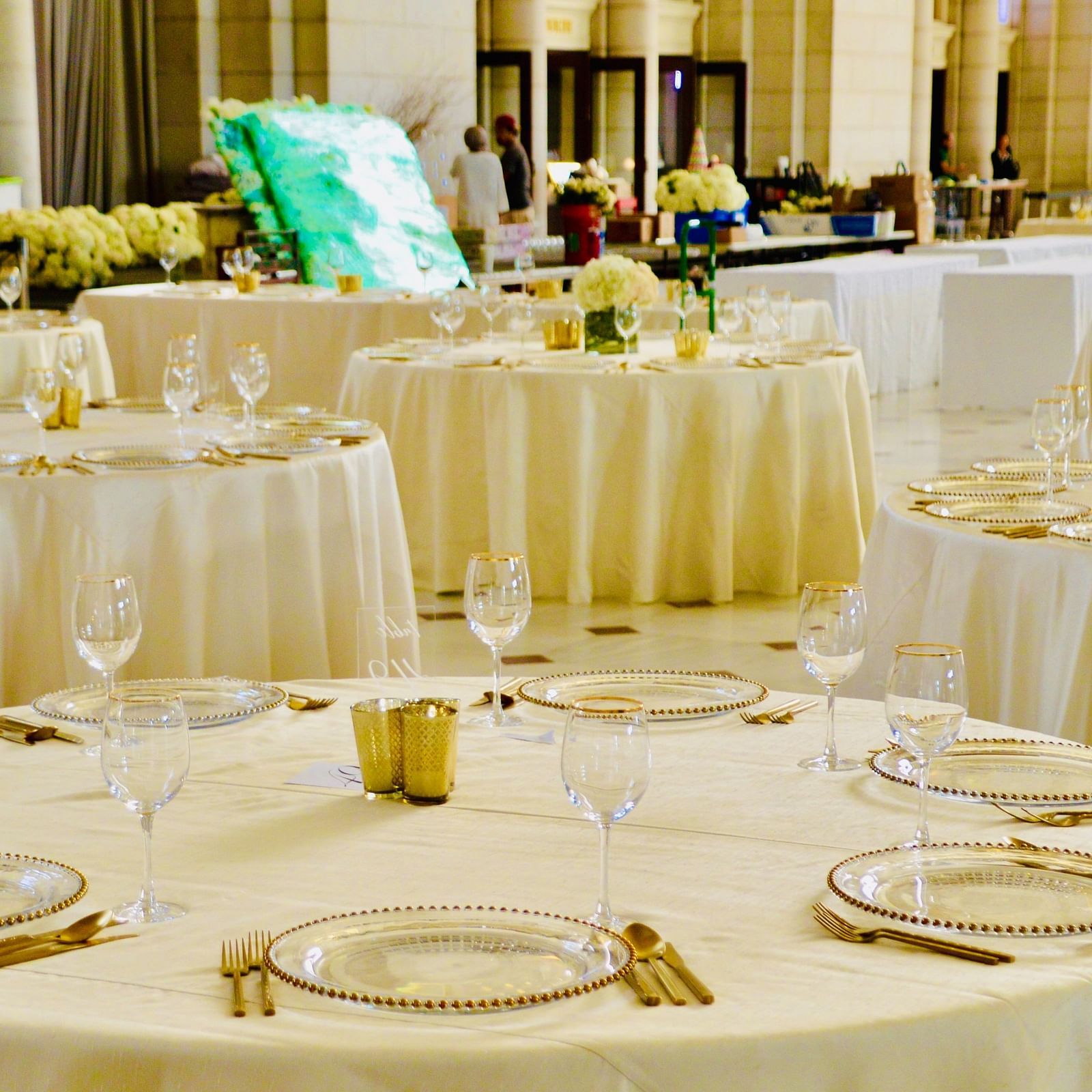 A banquet hall with round table seating arrangements and cutlery on the tables already set