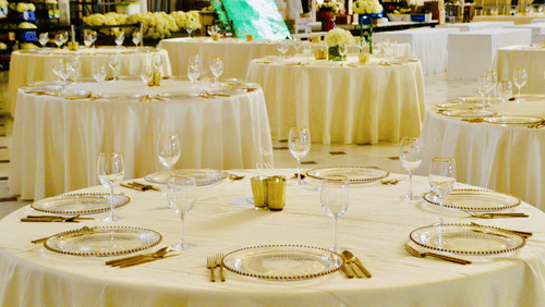 Banquet hall with round tables surrounded cloth covered chairs