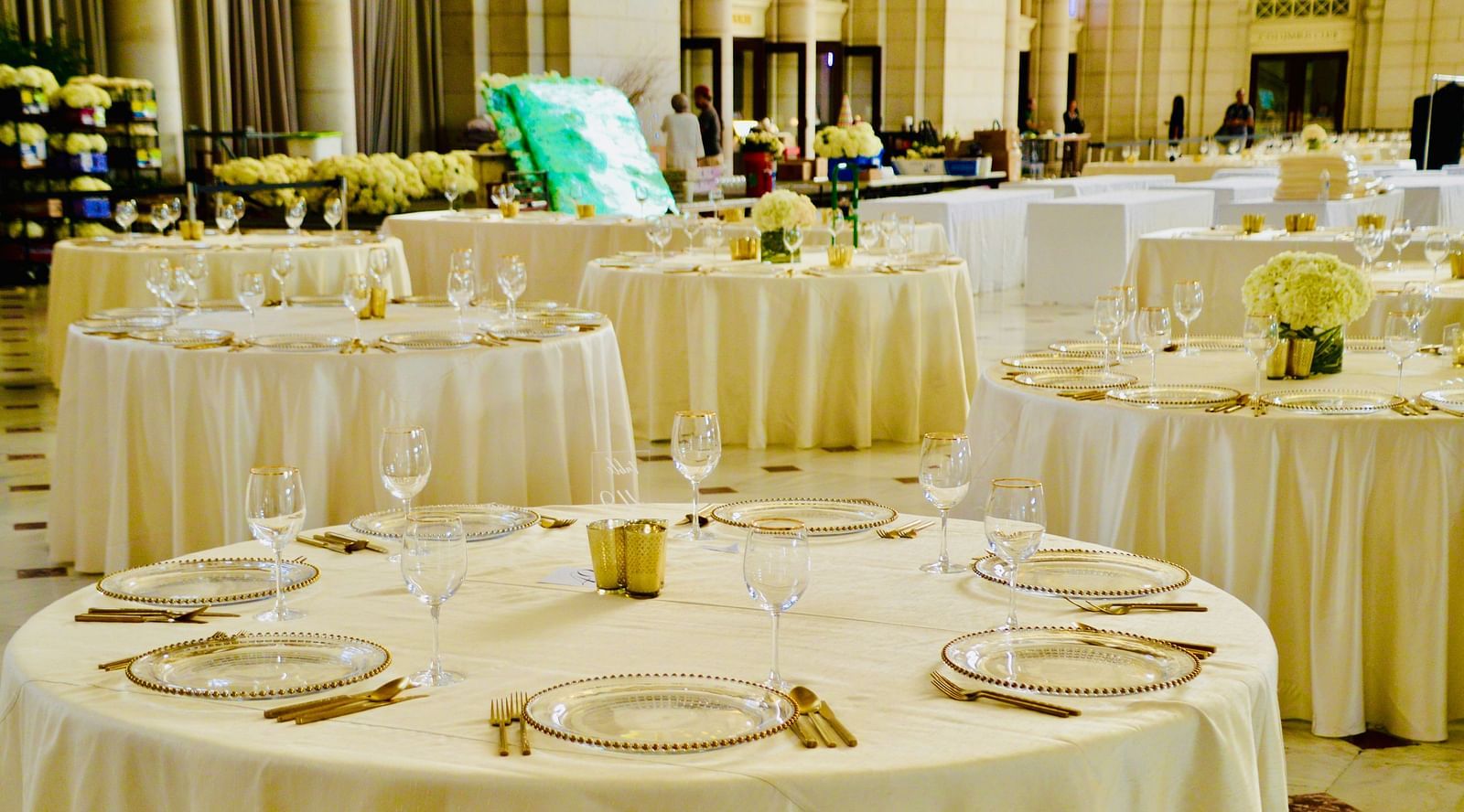 Cutlery placed on multiple round tables in a closed hall