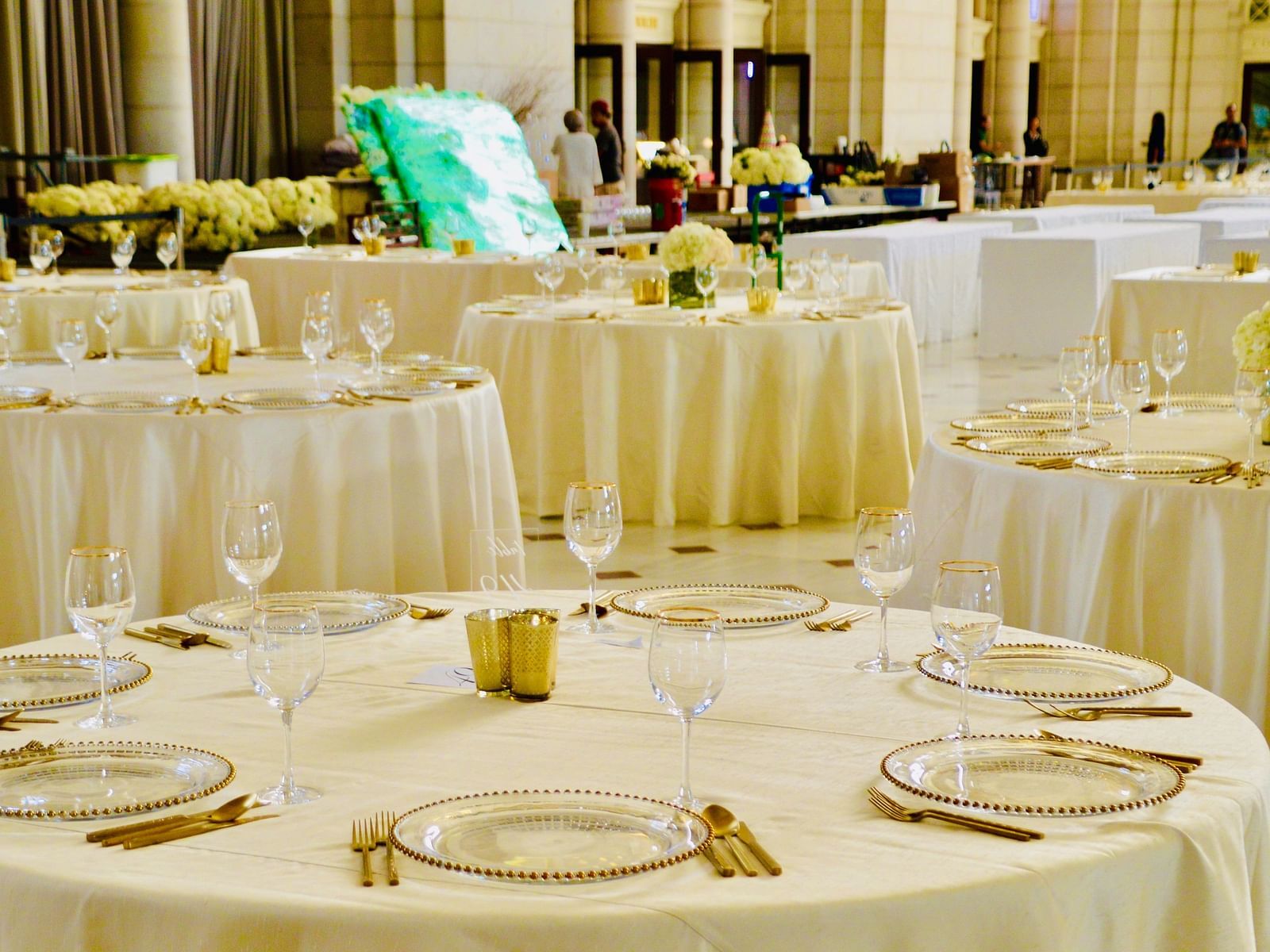 A banquet hall with round table seating arrangements and cutlery on the tables already set