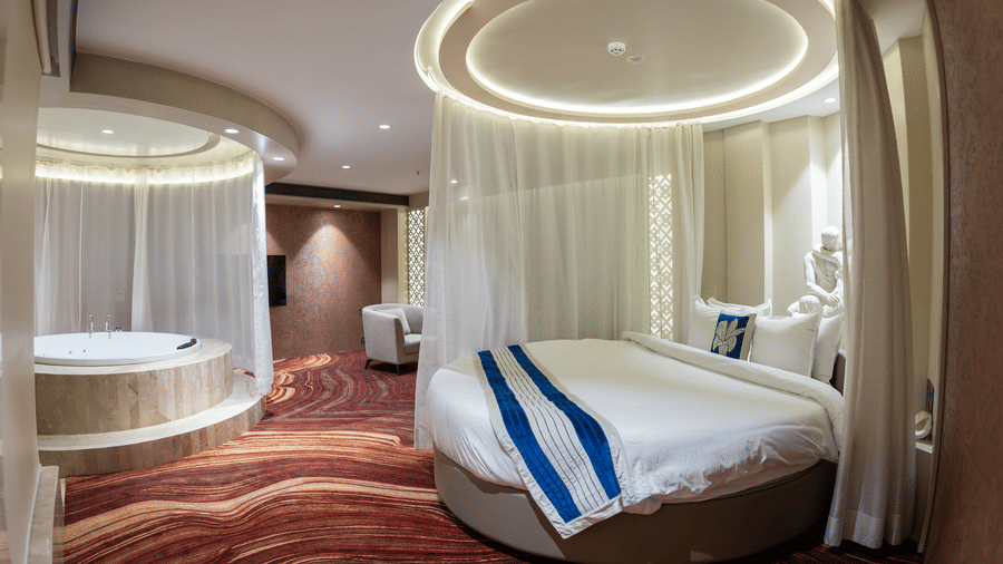 A view showing both the luxury circular bed and the integrated indoor jacuzzi in a premium suite - Praveg's Grand Eulogia, Ahmedabad