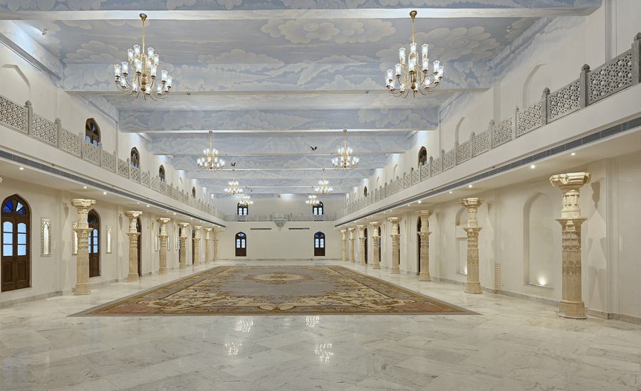 The illuminated banquet hall featuring white and cream decor with numerous chandeliers at Fateh Vilas, a wedding resort in Udaipur
