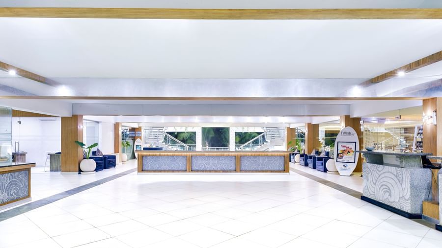A bright, spacious hotel lobby with a long reception desk and ample seating | Grand Bay Resort and Spa
