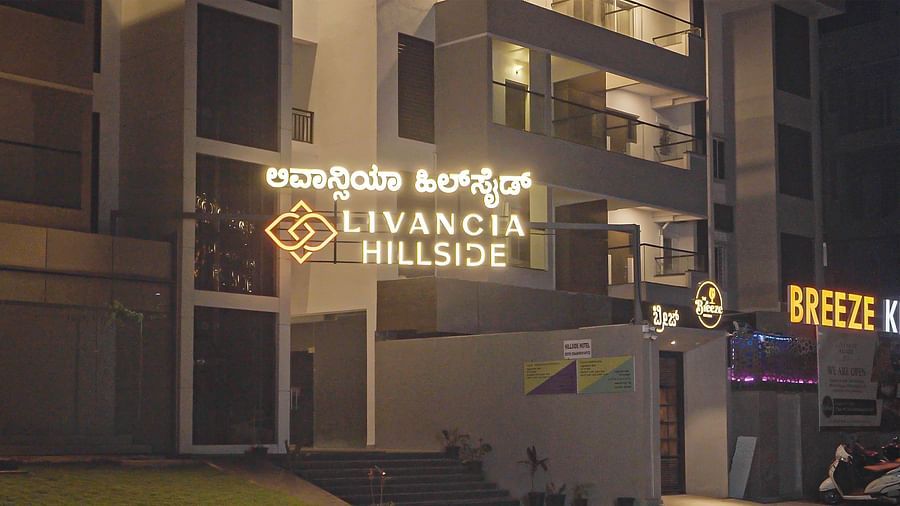 Closer view of the hotel entrance at night with illuminated signage and stairs leading up at TGI Livancia Hillside, JC Nagar, Mysore