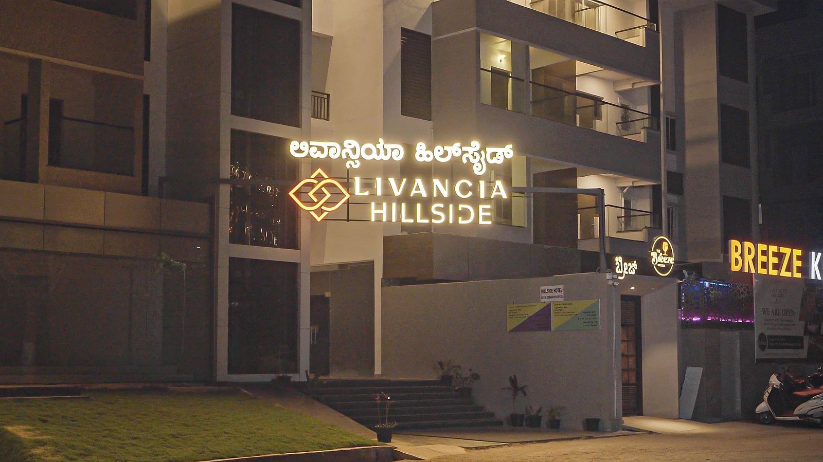 Closer view of the hotel entrance at night with illuminated signage and stairs leading up at TGI Livancia Hillside, JC Nagar, Mysore