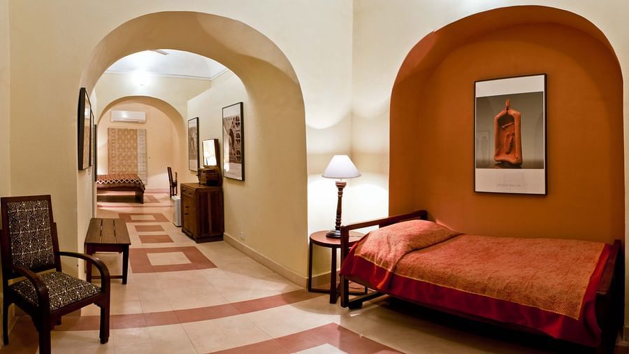 A hallway with arched doorways, a terracotta-colored alcove with a framed artwork and a daybed, and a patterned tile floor, showcasing the fort-palace's unique architectural details - Tijara Fort-Palace - 19th Century, Alwar.