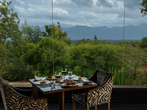 An outdoor dining area for two at The Sanctuary restaurant with a scenic view of the hills at The Serai Bandipur.