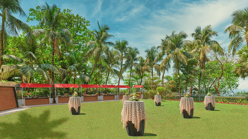 A wide view of a lawn with tables placed in it during the day at The Resort, Mumbai - A Wedding Resort in Mumbai